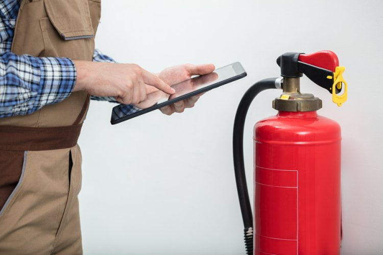 man with a tablet checking the extinguisher